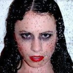 A fashion model intentionally made up to look like she is a zombie in the shower.